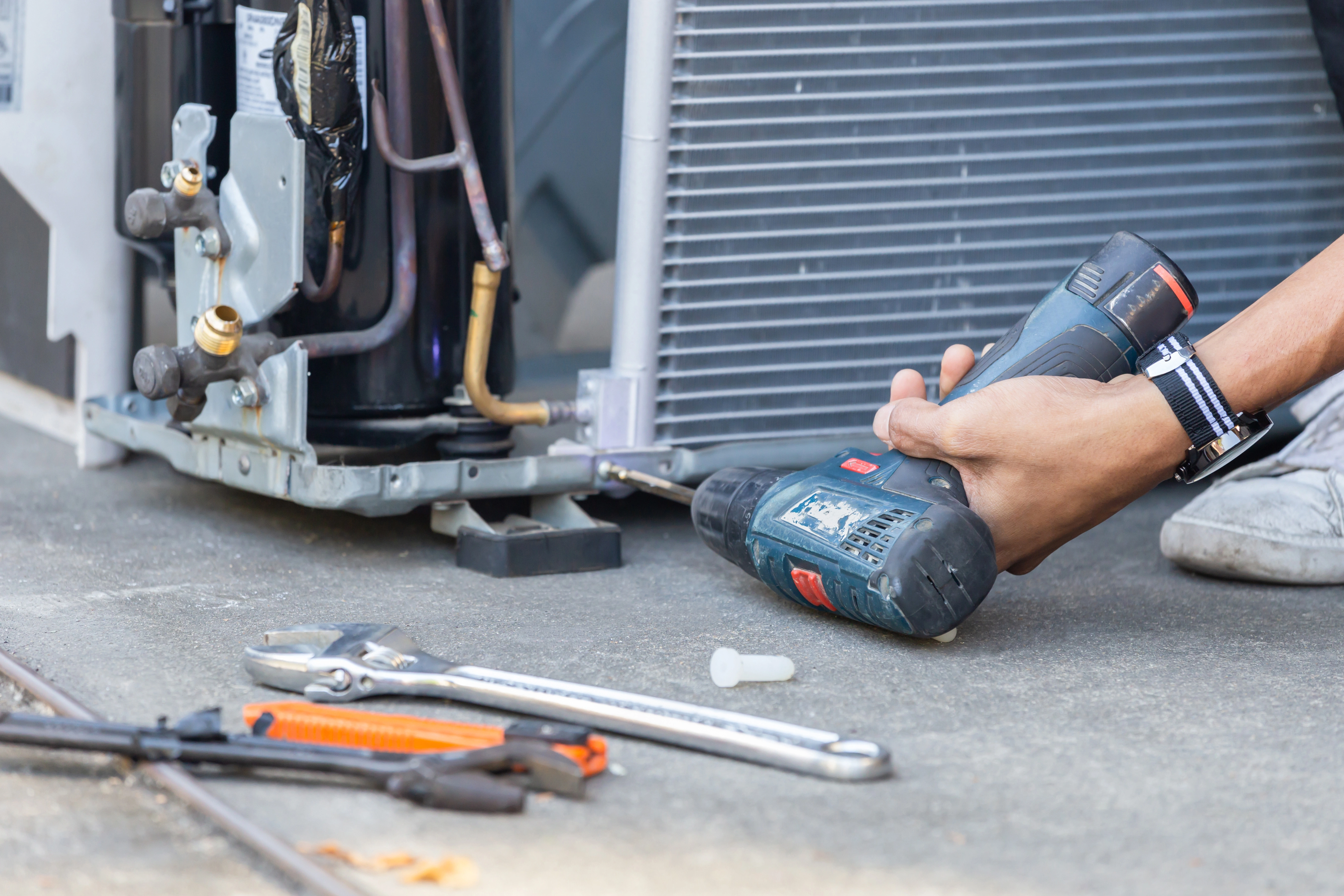 An Air Dynamics technician using a drill to assemble an AC compressor for a new installation in Tulsa.